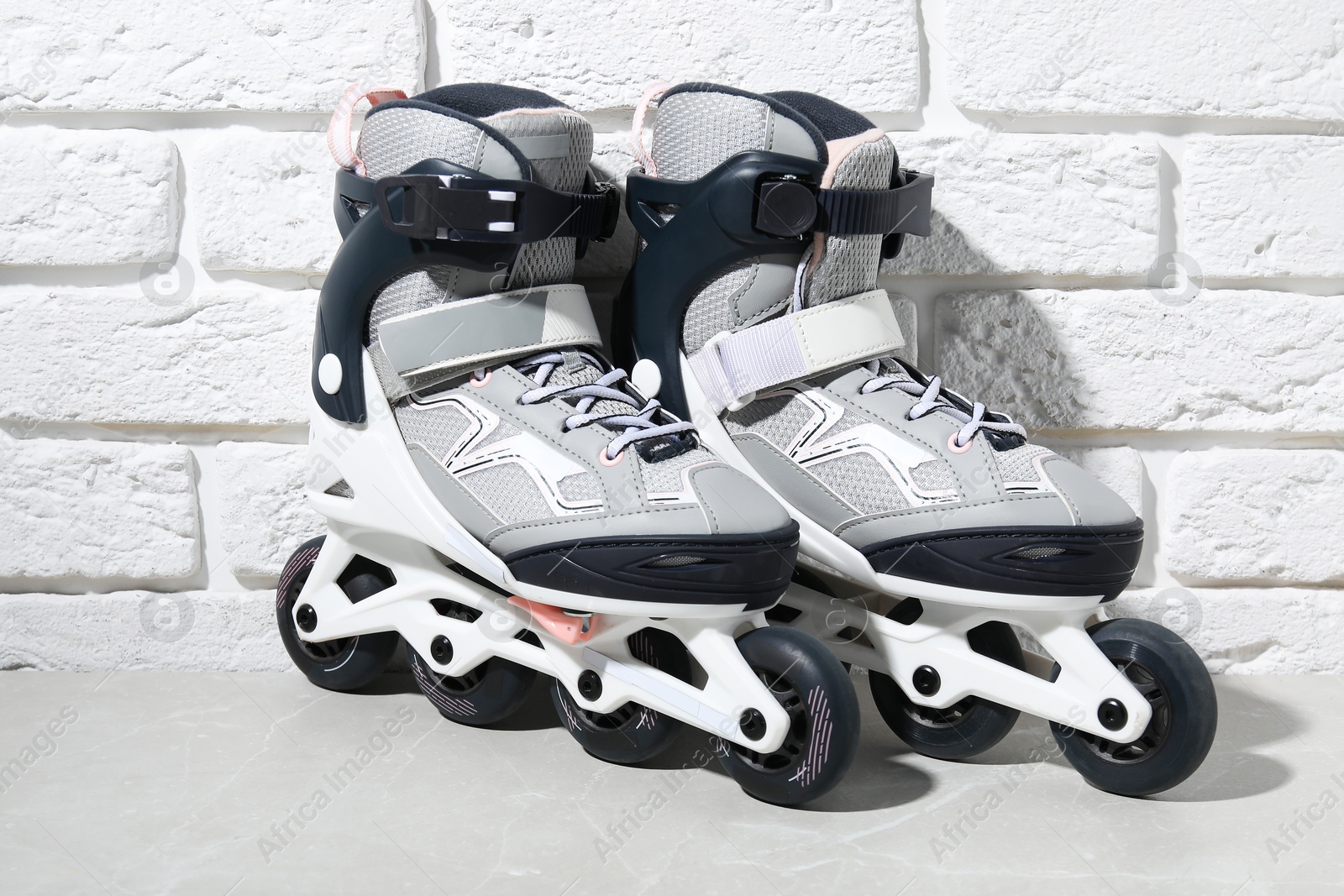 Photo of Pair of roller skates on grey marble table near white brick wall