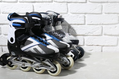 Photo of Roller skates on grey marble table near white brick wall, closeup. Space for text