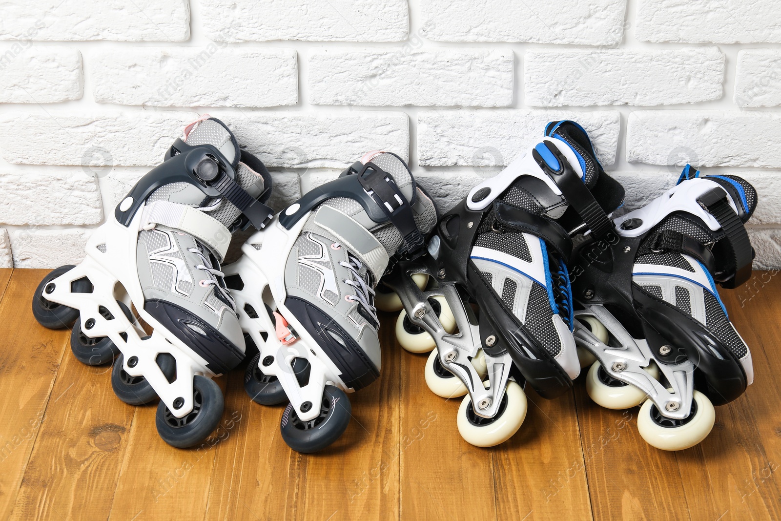 Photo of Roller skates on wooden table near white brick wall, above view