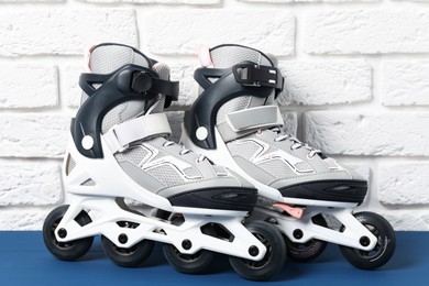 Photo of Pair of roller skates on blue table near white brick wall