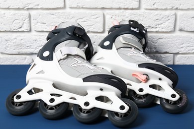 Photo of Pair of roller skates on blue table near white brick wall, closeup