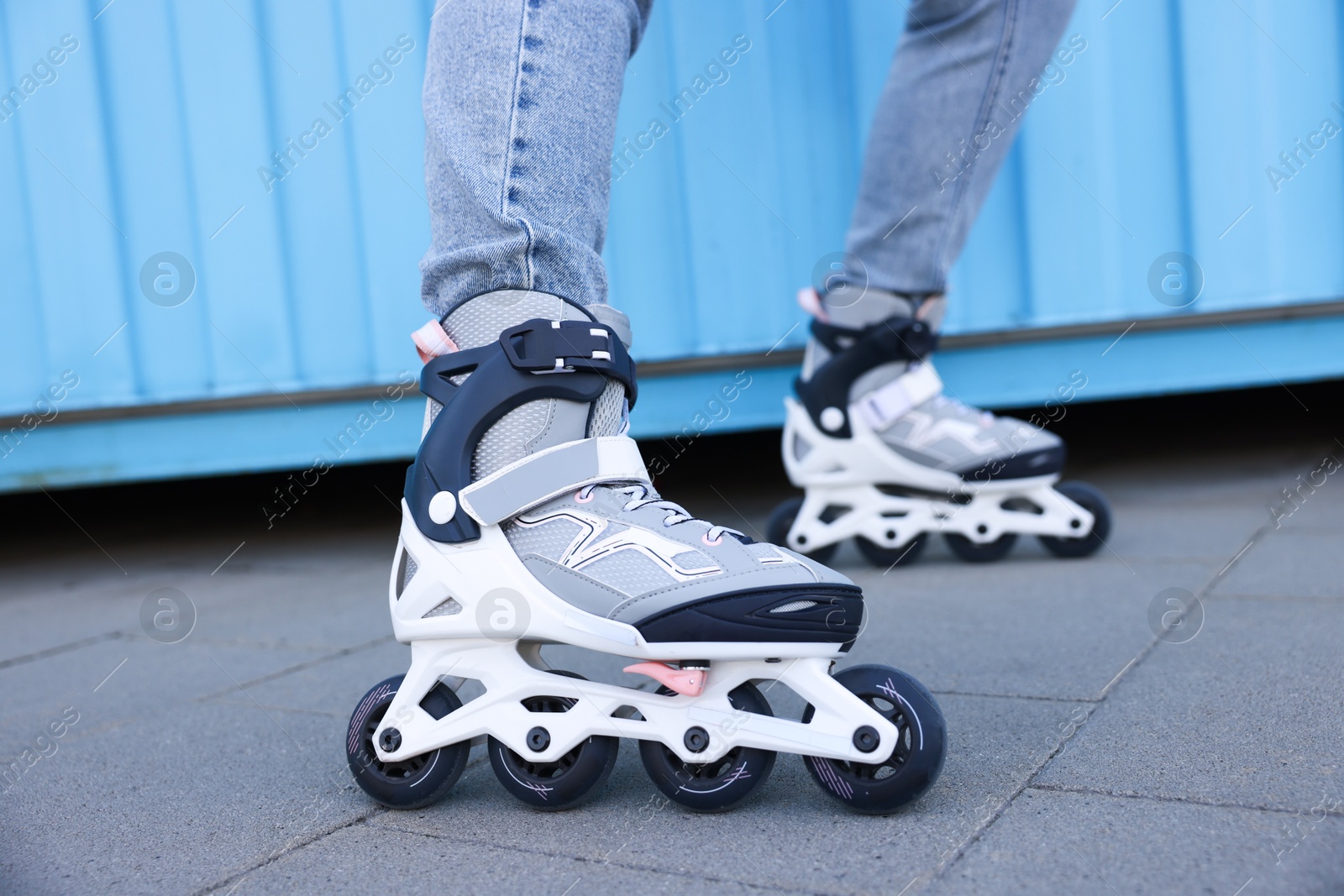 Woman with roller skates near light blue wall outdoors, closeup Photo of Woman with roller skates near light blue wall outdoors, closeup