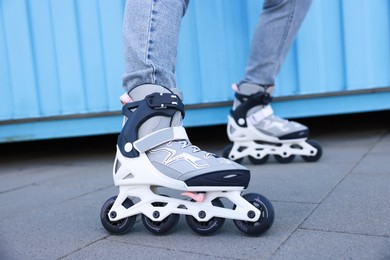 Photo of Woman with roller skates near light blue wall outdoors, closeup