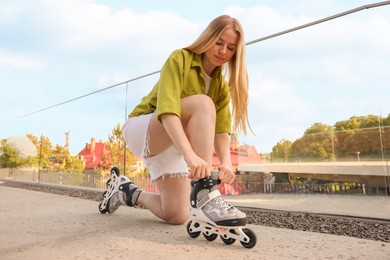 Photo of Happy woman putting on roller skates outdoors