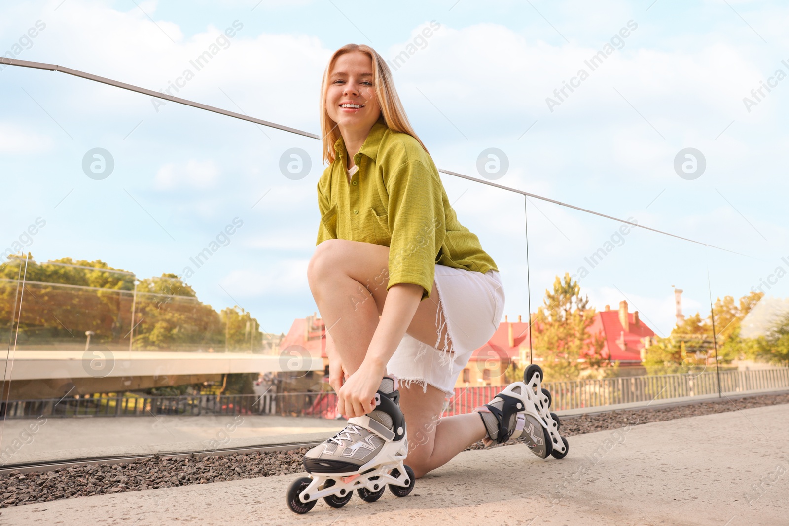 Photo of Happy woman putting on roller skates outdoors
