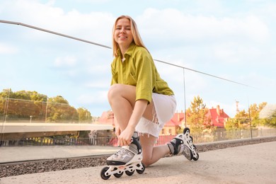 Photo of Happy woman putting on roller skates outdoors