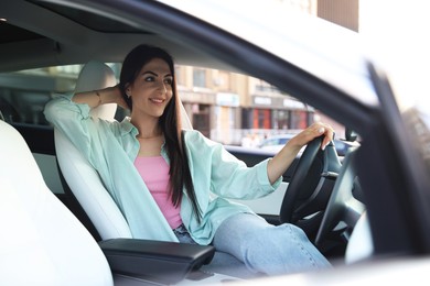 Photo of Woman holding steering wheel while driving car, view from outside