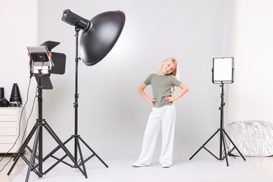 Photo of Little girl on light grey background in photo studio with professional equipment