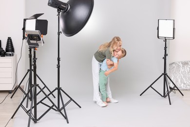 Photo of Little girl and her brother on light grey background in photo studio with professional equipment