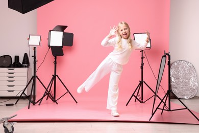 Photo of Little girl on pink background in photo studio with professional equipment