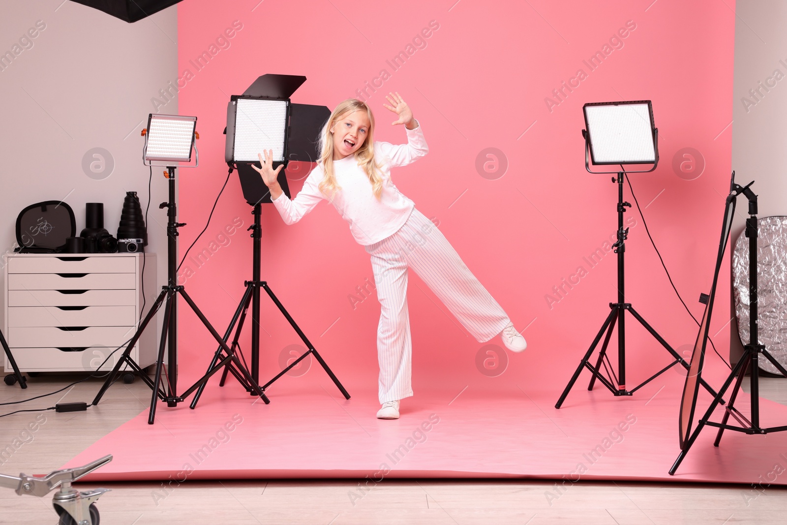 Photo of Little girl on pink background in photo studio with professional equipment
