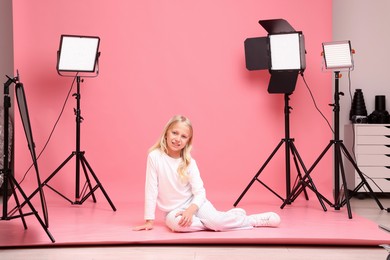 Photo of Little girl on pink background in photo studio with professional equipment