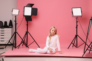 Photo of Little girl on pink background in photo studio with professional equipment
