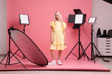 Photo of Little girl on pink background in photo studio with professional equipment