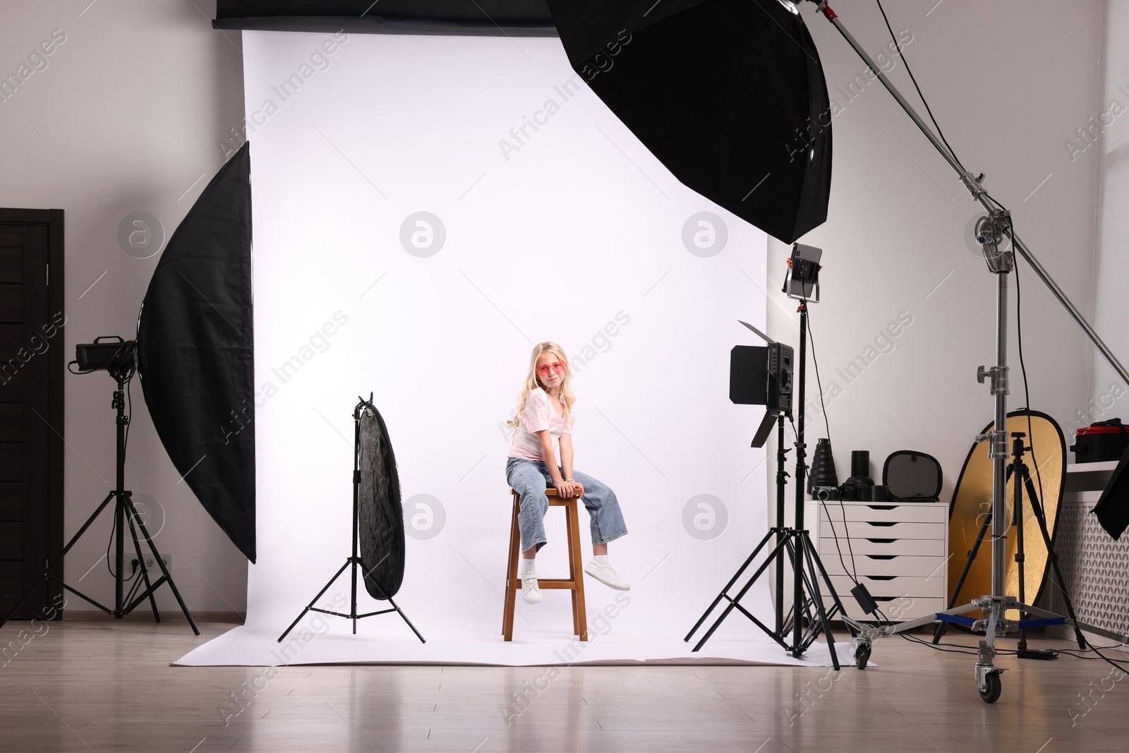 Little girl on white background in photo studio with professional equipment Photo of Little girl on white background in photo studio with professional equipment