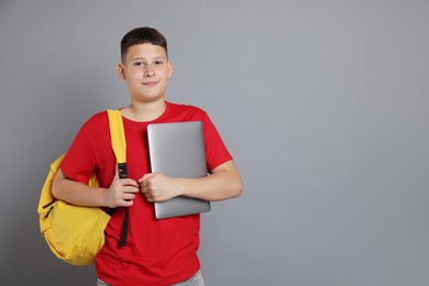 Photo of Teenage boy with laptop and backpack on grey background, space for text
