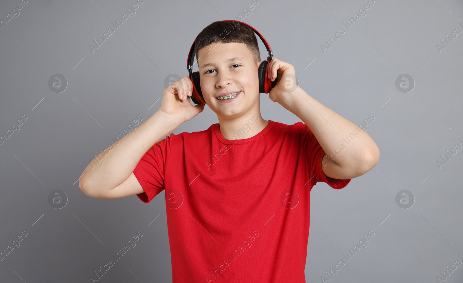 Photo of Teenage boy in headphones on grey background