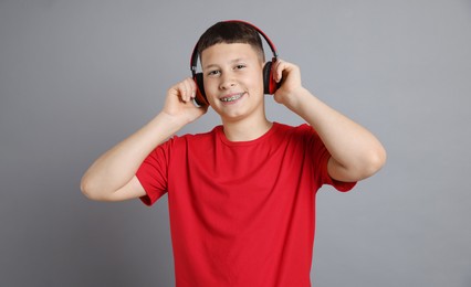 Photo of Teenage boy in headphones on grey background