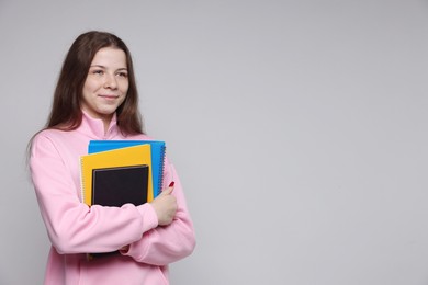 Photo of Teenage girl with notebooks on light grey background, space for text