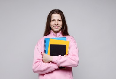 Photo of Teenage girl with notebooks on light grey background