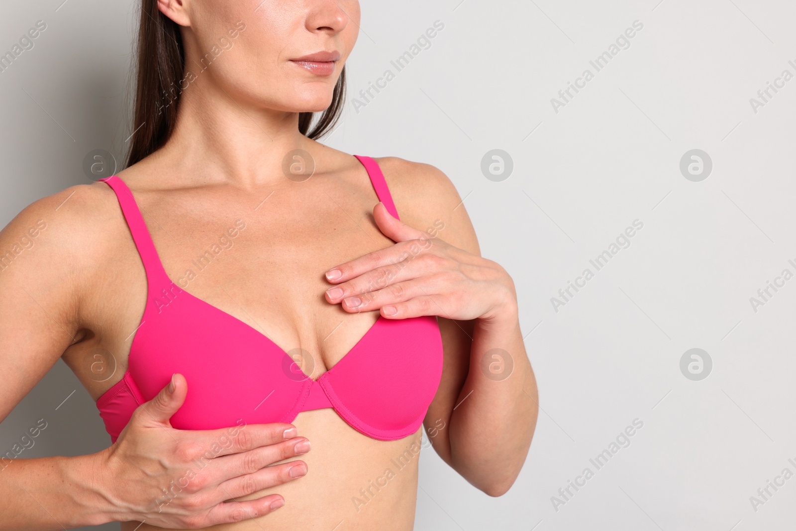 Woman wearing beautiful pink bra on light grey background, closeup. Space for text Photo of Woman wearing beautiful pink bra on light grey background, closeup. Space for text