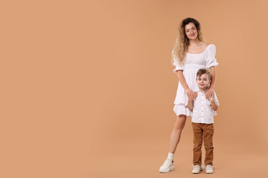 Photo of Family. Happy mother and her son on beige background. Space for text