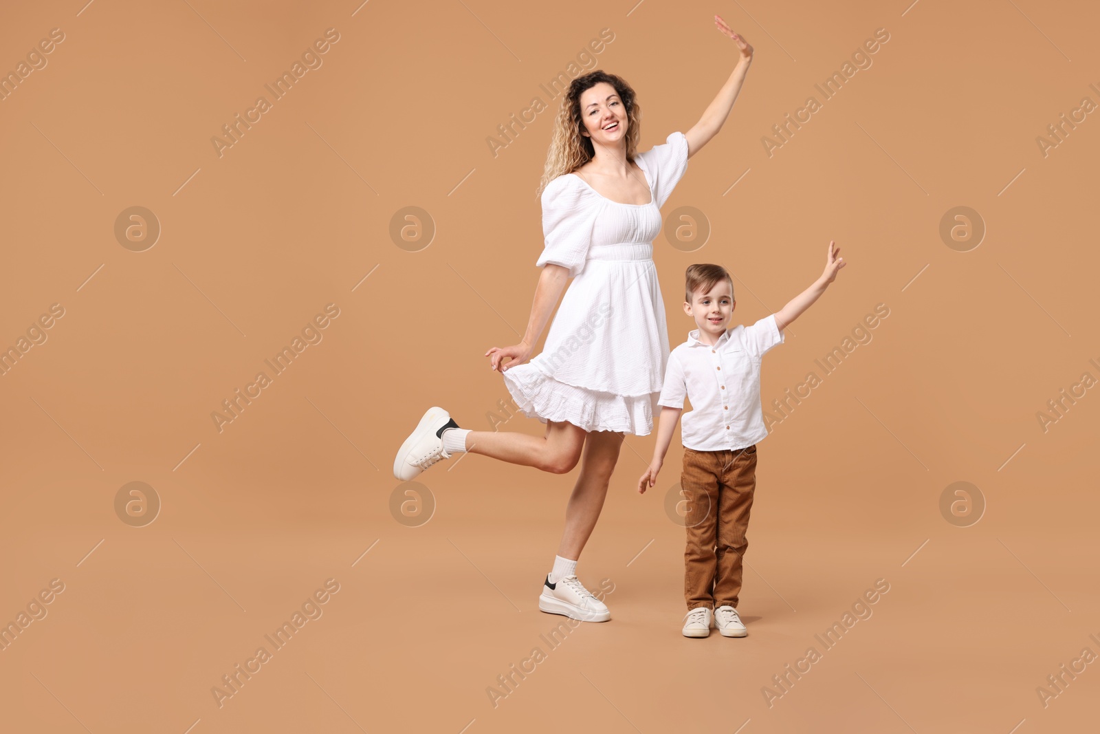 Photo of Family. Happy mother and her son posing on beige background. Space for text