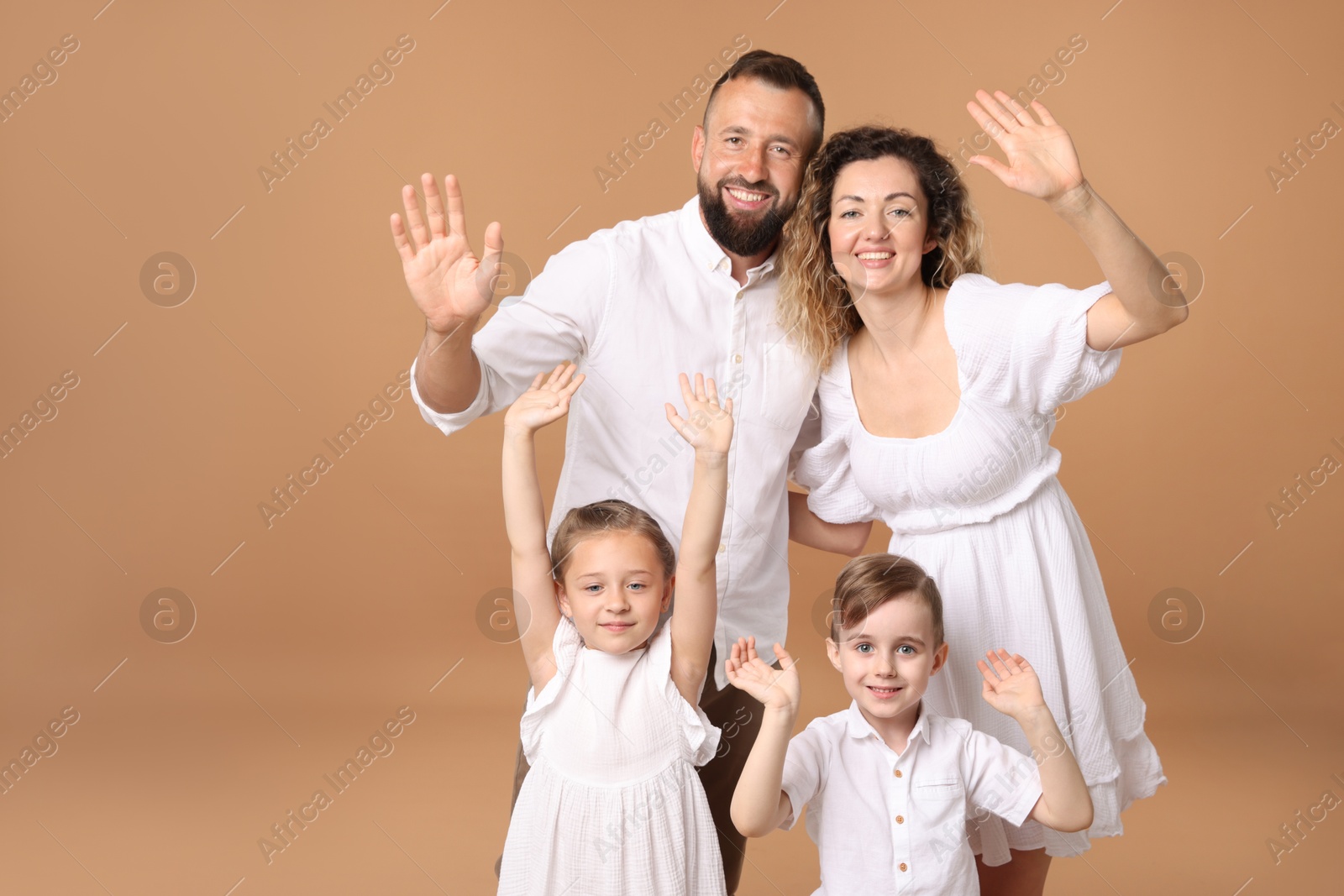 Photo of Portrait of happy family waving hello on beige background