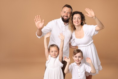 Photo of Portrait of happy family waving hello on beige background