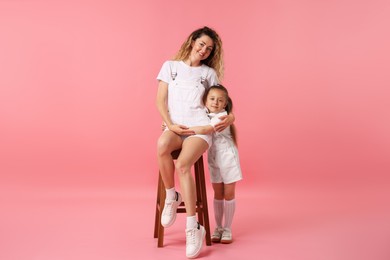 Photo of Family. Happy mother and her daughter posing on pink background