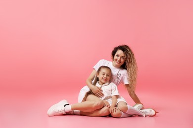Photo of Family. Happy mother and her daughter posing on pink background. Space for text