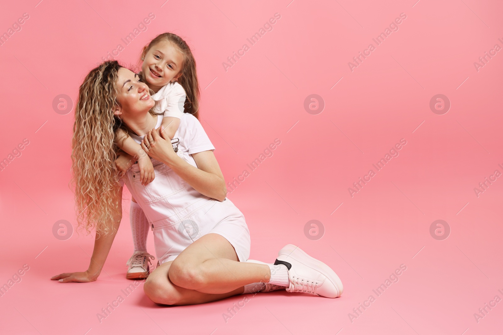 Photo of Family. Happy mother and her daughter posing on pink background. Space for text