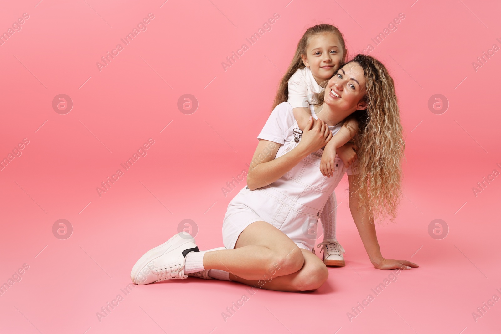 Photo of Family. Happy mother and her daughter posing on pink background. Space for text
