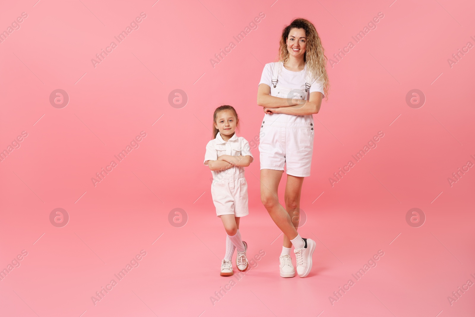 Photo of Family. Happy mother and her daughter posing on pink background