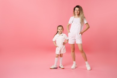 Photo of Family. Happy mother and her daughter posing on pink background. Space for text