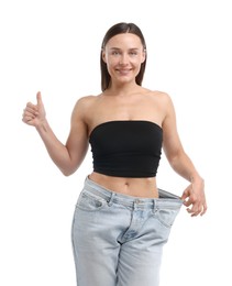Photo of Fit woman wearing old jeans after weight loss and showing thumbs up on white background