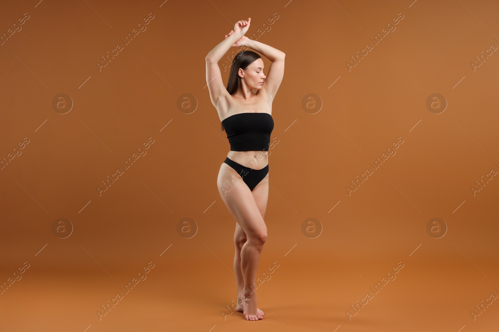 Photo of Fit woman with perfect body on brown background