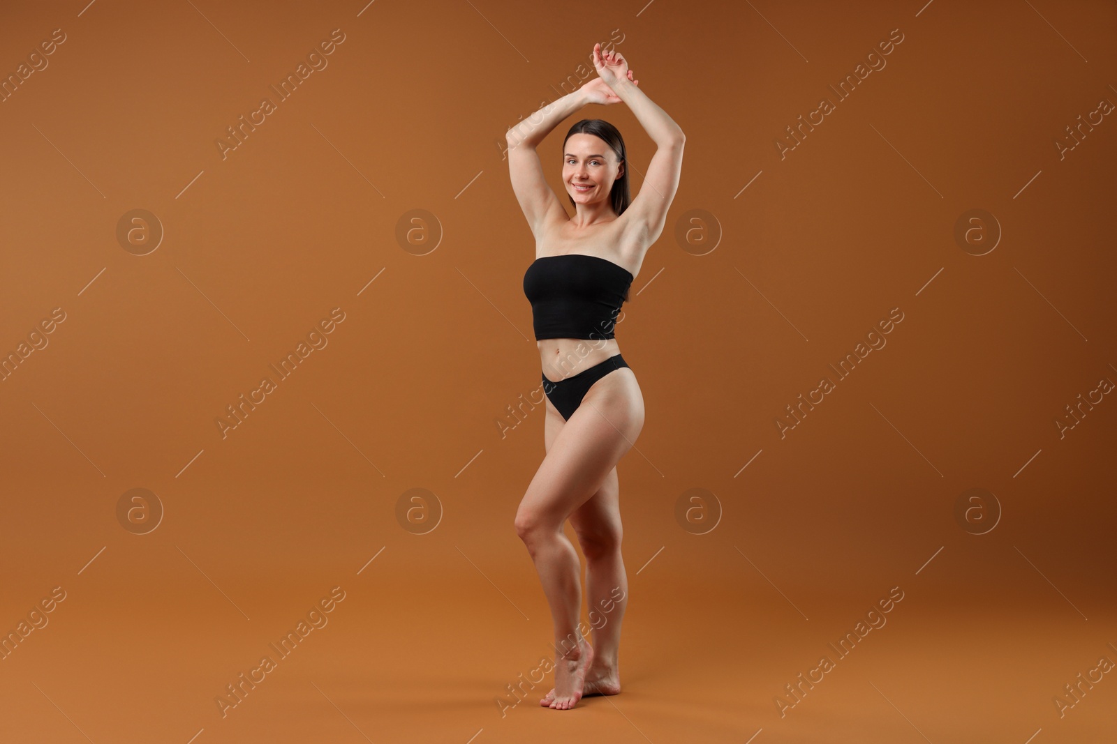 Fit woman with perfect body on brown background Photo of Fit woman with perfect body on brown background