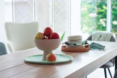 Photo of Apples and clean dishware on wooden table in dining room