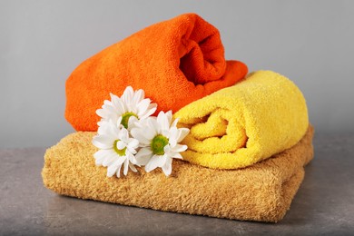 Photo of Colorful towels and chrysanthemum flowers on grey table, closeup
