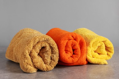 Photo of Rolled colorful towels on grey table, closeup