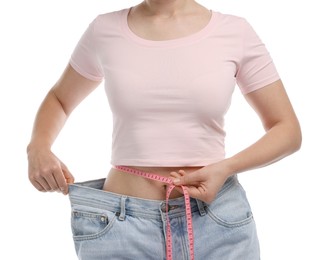 Photo of Woman with measuring tape wearing old jeans after weight loss on white background, closeup
