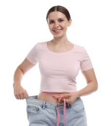 Photo of Beautiful woman with measuring tape wearing old jeans after weight loss on white background