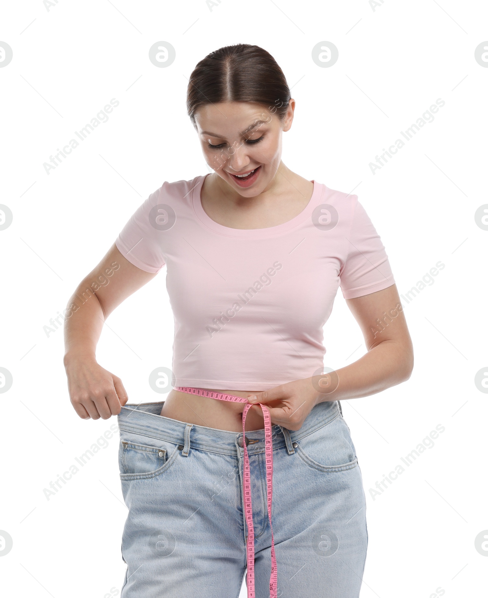 Beautiful woman with measuring tape wearing old jeans after weight loss on white background Photo of Beautiful woman with measuring tape wearing old jeans after weight loss on white background