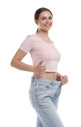Photo of Beautiful woman wearing old jeans after weight loss and showing thumbs up on white background