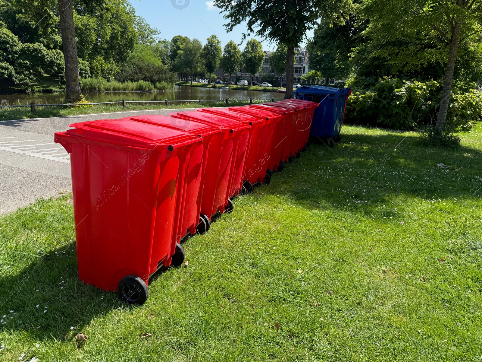 Photo of Many color trash bins on green grass in park, space for text