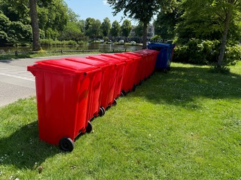 Photo of Many color trash bins on green grass in park, space for text