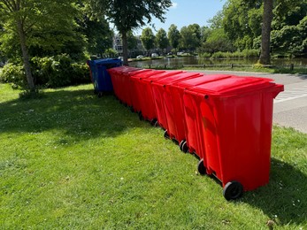 Photo of Many color trash bins on green grass in park, space for text