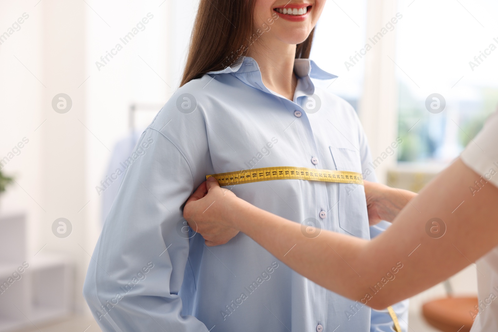 Photo of Tailor measuring woman's chest with tape in atelier, closeup