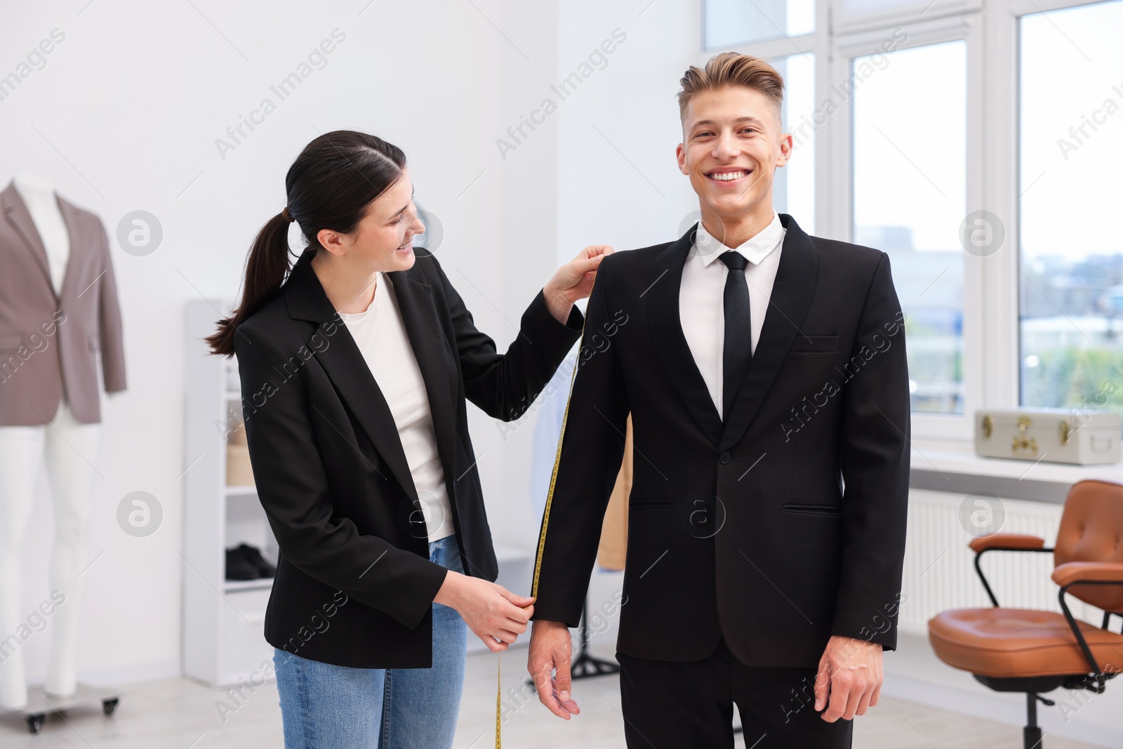 Photo of Tailor measuring jacket on man in atelier